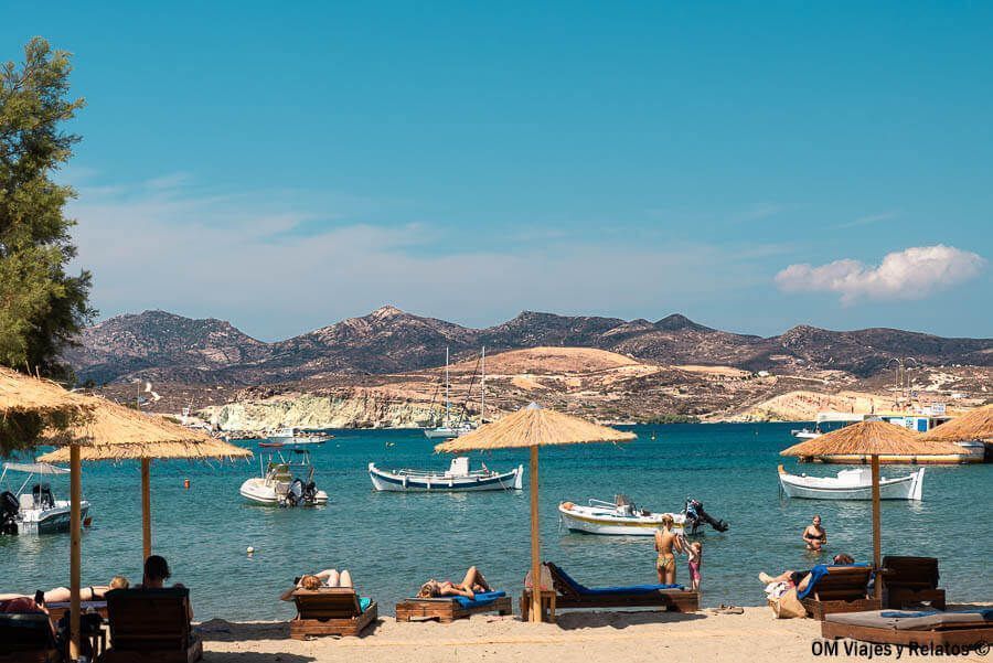 Ambiente relajado en Pollonia Beach, una de las mejores playas de Milos, con sombrillas, tumbonas y vistas al mar cristalino.