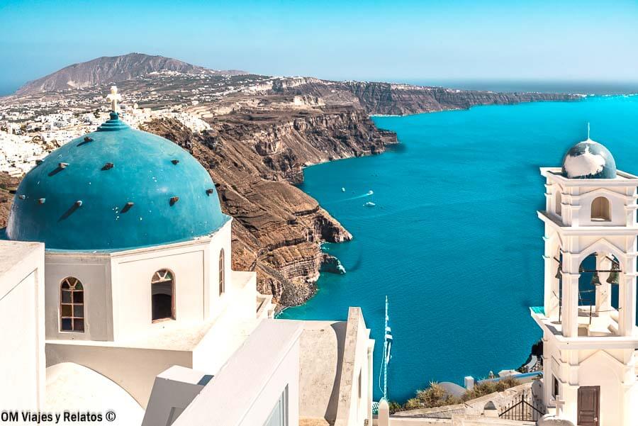Iglesias de cúpulas azules con vistas a la caldera de Santorini, una imagen perfecta para hablar de donde dormir en Santorini.
