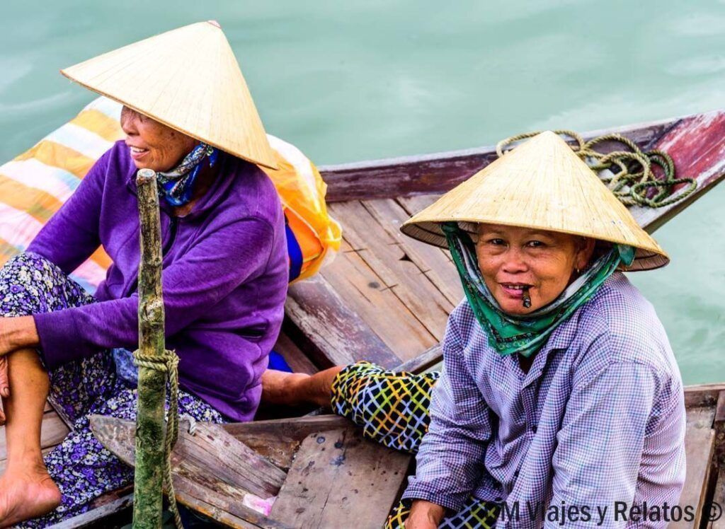 Dos mujeres con sombrero cónico en una barca de madera sobre agua del río Mekong, consejos para viajar a vietnam por libre