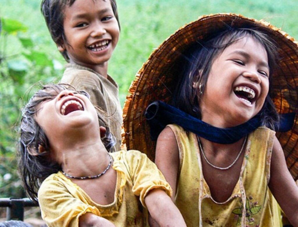 Niños vietnamitas riendo y jugando, escena cotidiana para consejos para viajar a Vietnam por libre.