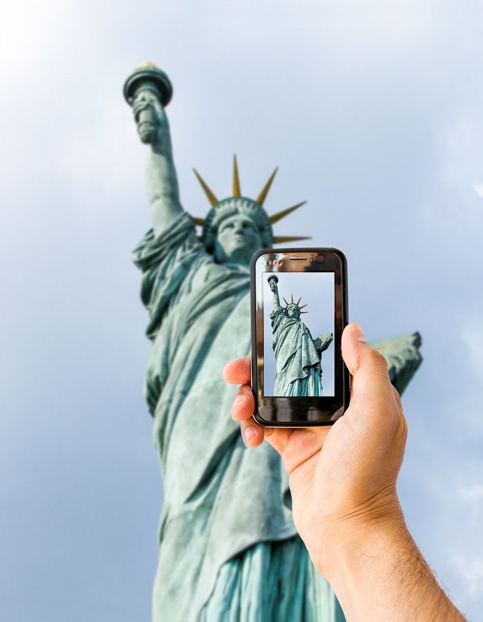 Móvil fotografiando la Estatua de la Libertad en Nueva York, una imagen viajera para explicar como tener internet en Estados Unidos.
