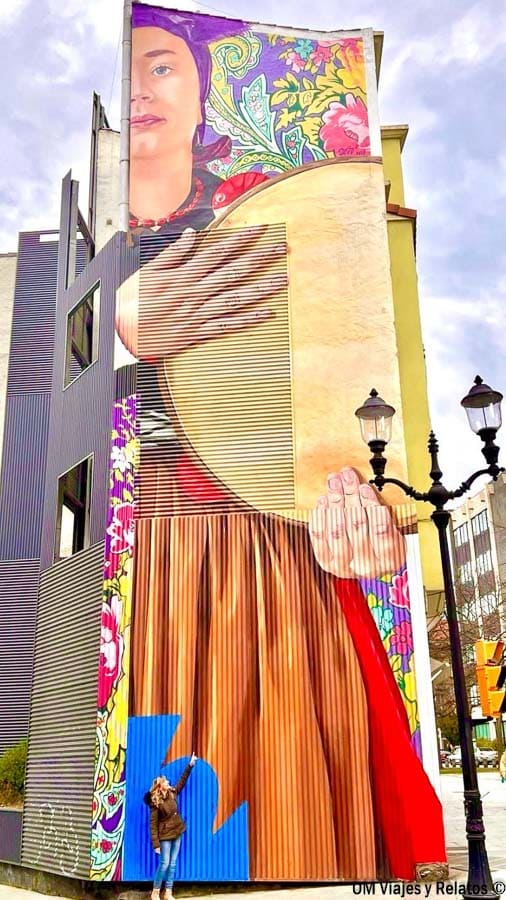 Foto mía junto a un mural de arte urbano en Gijón, una muestra de la cultura contemporánea que descubrir durante 7 dias por Asturias en coche.