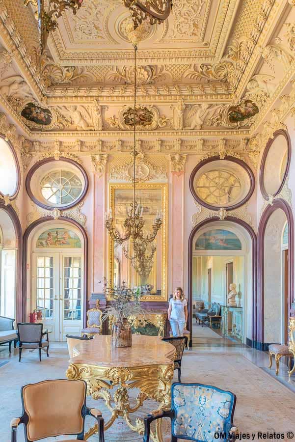 Foto mía en el salón palaciego de la Pousada Palácio de Estoi con decoración barroca y lámparas, una visita imprescindible que ver en Algarve en 3 días.