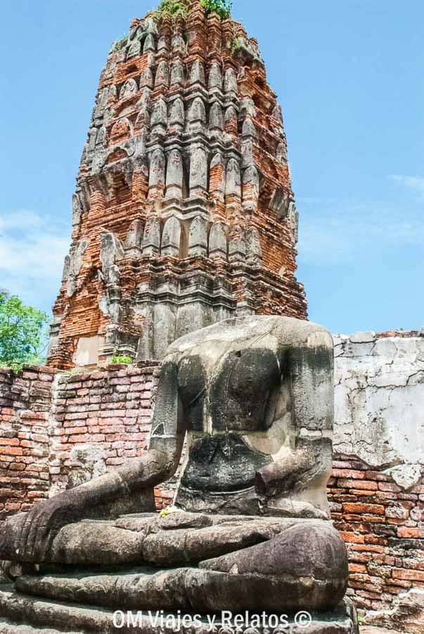 Buda de piedra erosionado ante torre de ladrillo rojo en Ayutthaya en un día de recorrido por los templos