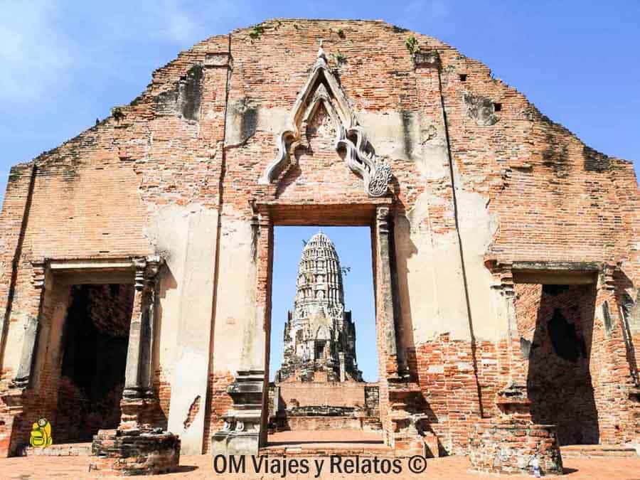 Puerta de templo en ruinas con estupa al fondo bajo cielo azul en Ayutthaya en un día de viaje por Tailandia