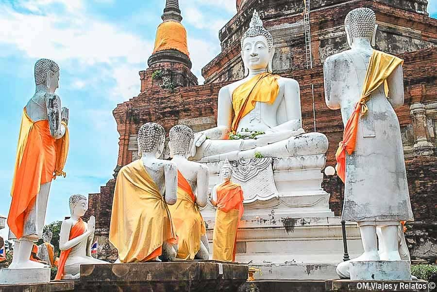 Conjunto de estatuas de Buda blanco con túnicas naranjas en Ayutthaya en un día de visita a sus templos