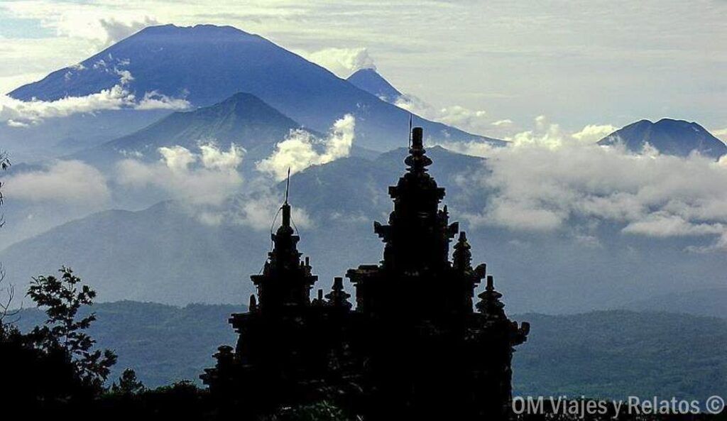 Silueta de un templo con volcanes entre nubes, una postal inolvidable para una ruta por Indonesia en 15 días por libre.