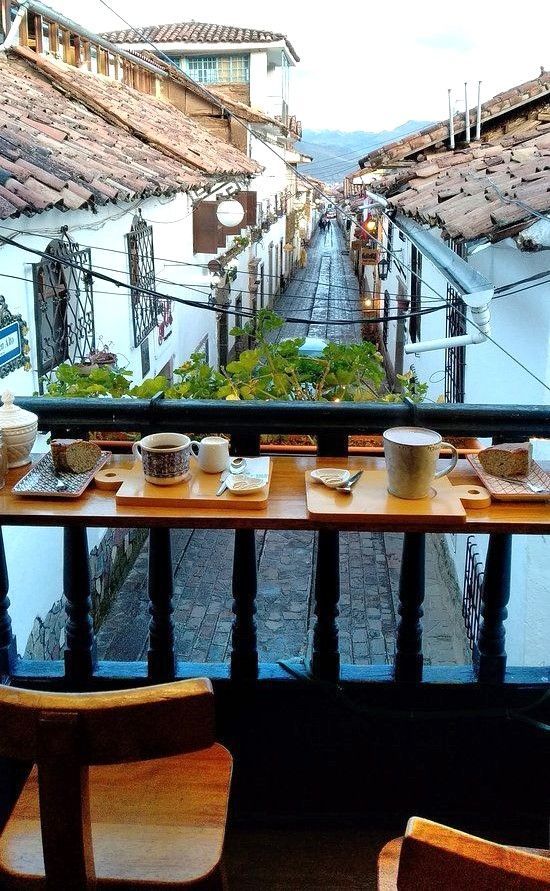 Desayuno en un balcón con vistas a una calle empedrada del centro de Cusco, un plan bonito de que ver en Cusco y alrededores.