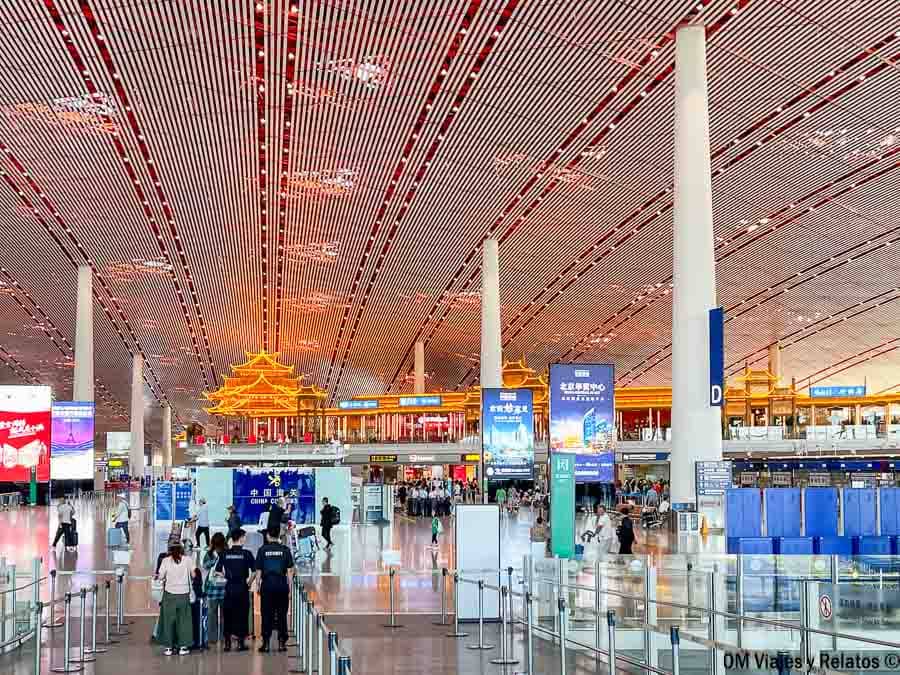 Interior de la terminal del aeropuerto de Pekín con mostradores y viajeros, como ir del aeropuerto de Pekín al centro.