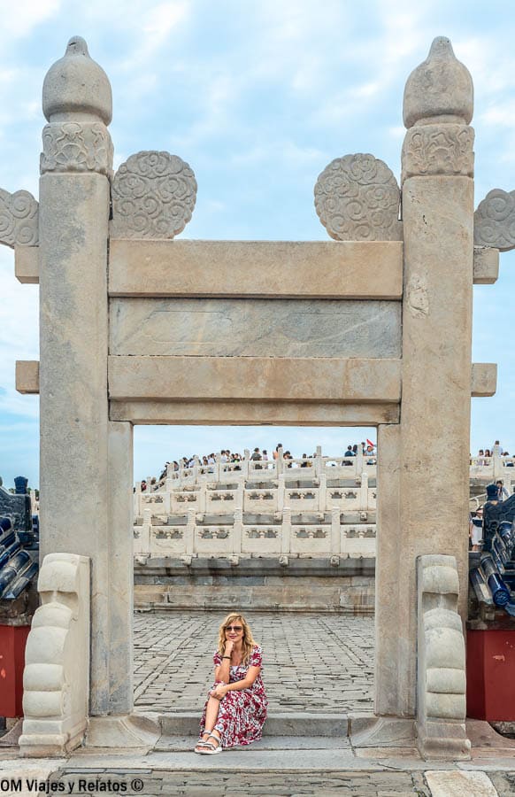 Foto mía sentada bajo un arco de piedra en el recinto, una foto perfecta al visitar el Templo del Cielo de Pekín.