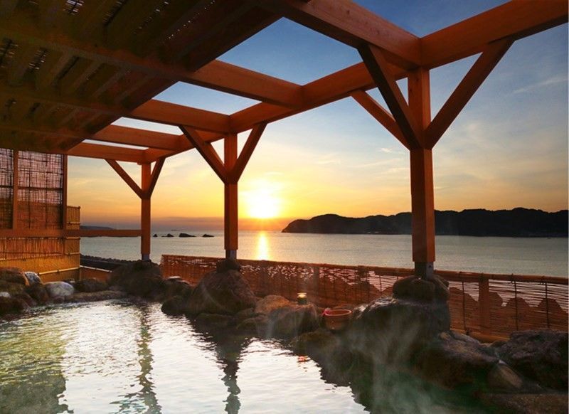 Onsen al aire libre junto al mar al atardecer, una de las experiencias más relajantes de aguas termales en Japón.