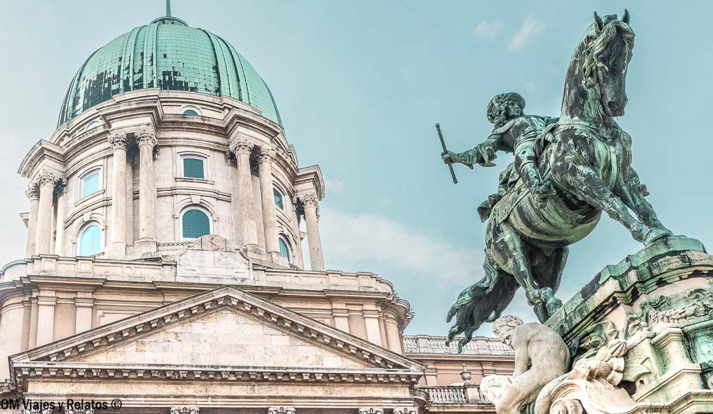 Que ver en el Castillo de Buda: estatua ecuestre frente a la cúpula verde del Palacio Real en Budapest.