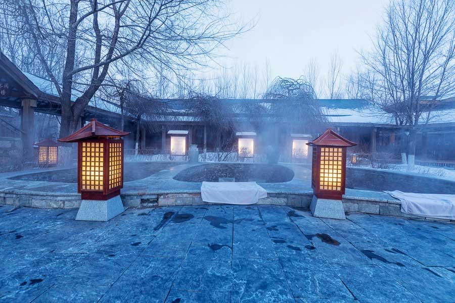 Onsen al aire libre con faroles y vapor en invierno, consejos para viajar a Japón por libre: llevar toalla pequeña y seguir las normas del baño.
