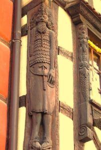 Escultura tallada en madera en la fachada de una casa tradicional, uno de los detalles curiosos que ver en Riquewihr paseando por sus calles.