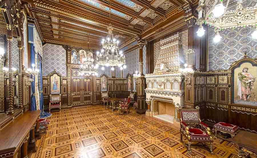 Que ver en el Castillo de Buda: interior de una sala del Palacio Real con techo de madera, lámparas de araña y chimenea decorada.