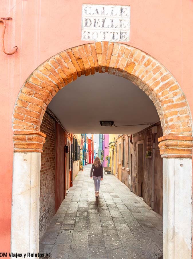 Foto mía caminando por un callejón con arco de ladrillo y casas de colores en Burano, una escena con encanto de que ver en Burano.