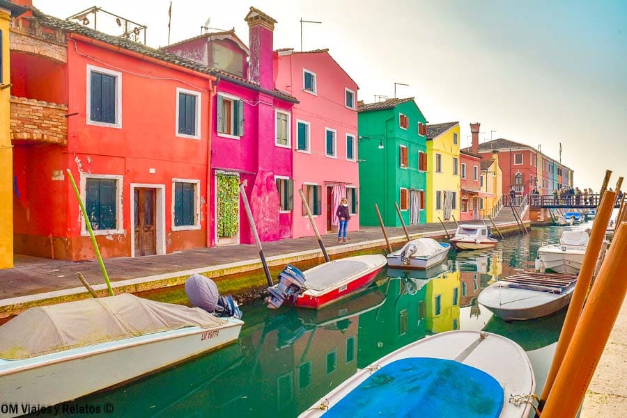 Foto mía en el canal de Burano con barcas y casas de colores (rojo, rosa, verde y amarillo), una postal imprescindible de que ver en Burano.