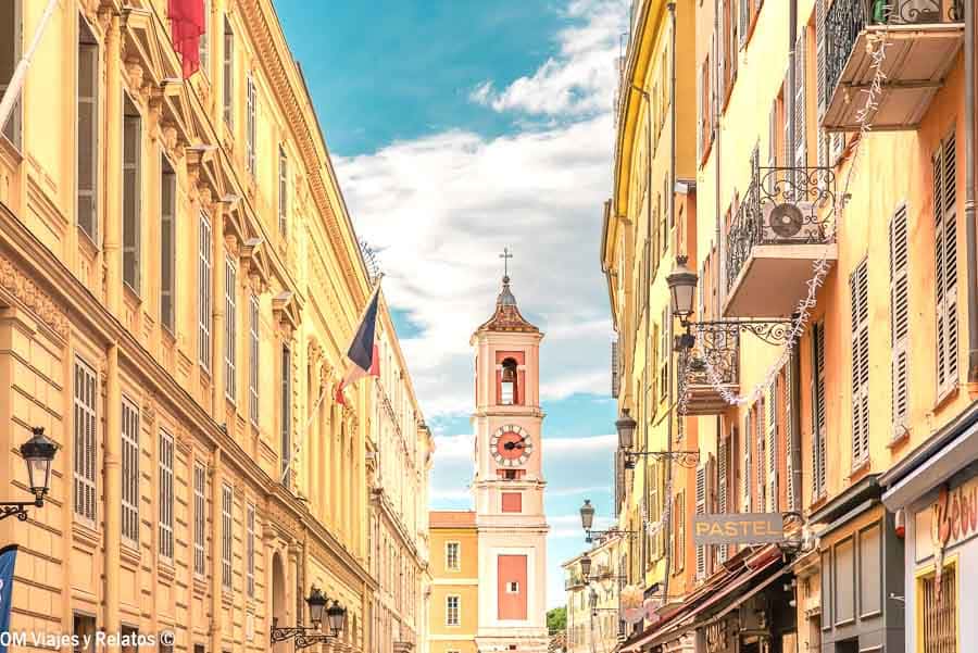 Calle del centro histórico de Niza con fachadas color pastel y campanario al fondo, una parada imprescindible en una ruta por la Costa Azul.