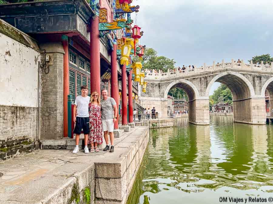 Foto familiar de OM Viajes y Relatos posando junto a un canal y un puente tradicional en China, una imagen de viaje que acompaña una guía sobre como pagar en China.