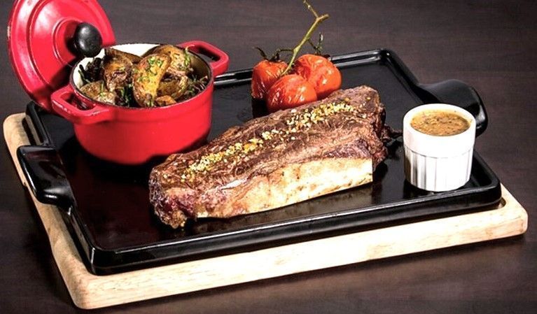 Costilla de ternera servida con guarnición y salsa en Oh! Le Bistro, un plan gastronómico top en una ruta por Aquitania.