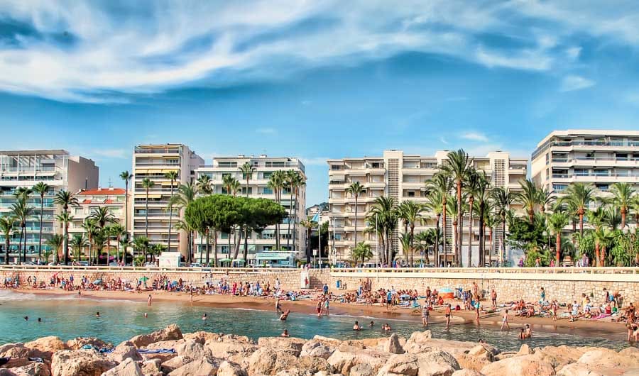 Playa urbana de Cannes con palmeras y edificios frente al mar, uno de los lugares que ver en Cannes.