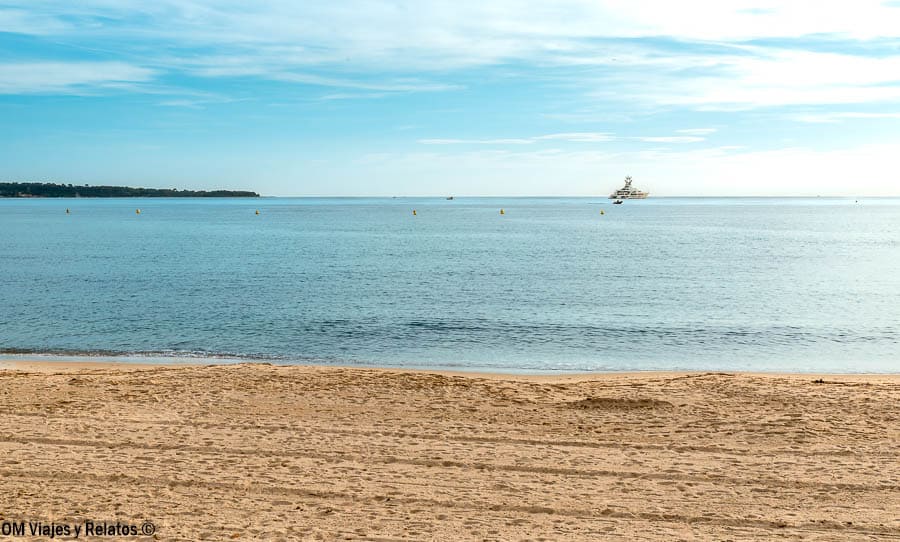 Playa tranquila con vistas al mar Mediterráneo y yate al fondo, paisaje imprescindible que ver en Cannes.