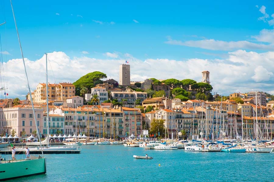 Vistas del puerto de Cannes con veleros y casas de colores frente a la colina del Suquet, imprescindible de que ver en Cannes.