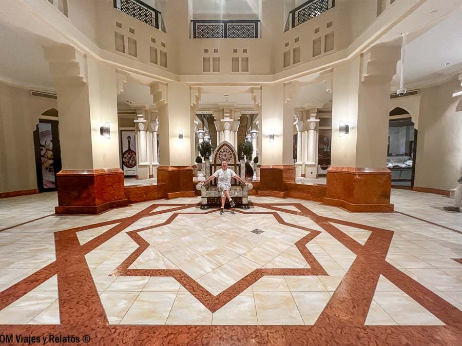 JC sentada en el lobby de un hotel en Dubái con arquitectura de estilo árabe, una imagen útil para preparar consejos para viajar a Dubai.