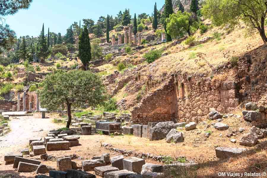 Vistas del yacimiento arqueológico de Delfos en la ladera, con ruinas y cipreses, ideal para visitar el Oráculo de Delfos.