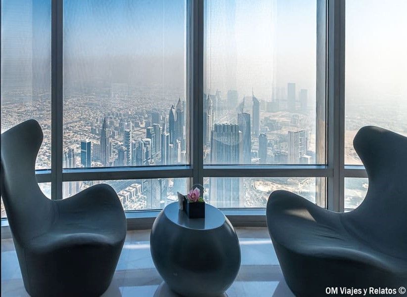 Subir al Burj Khalifa: sillones y mesa junto a los ventanales del mirador, con vistas panorámicas del skyline de Dubái.