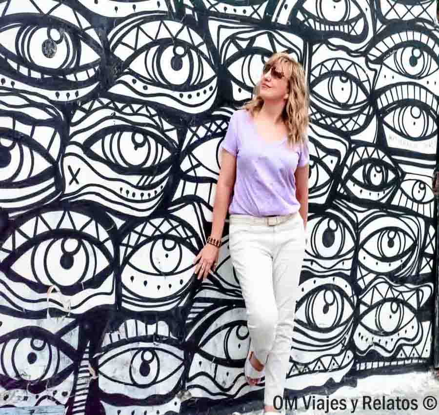Servidora posando frente a un mural de arte urbano con ojos en Atenas, una visita original para incluir en una ruta sobre que ver en Atenas en 2 días.
