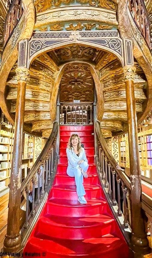Foto mía sentada en la escalera roja de la Librería Lello, la famosa libreria de Harry Potter en Oporto.
