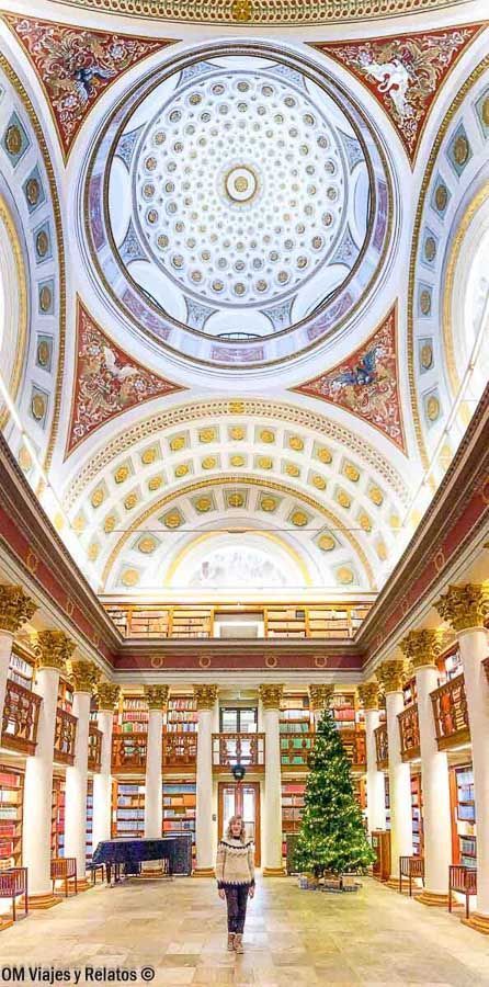 Una servidora en el salón central de la biblioteca histórica de Helsinki bajo una cúpula ornamentada, parada cultural que ver en Helsinki en un día