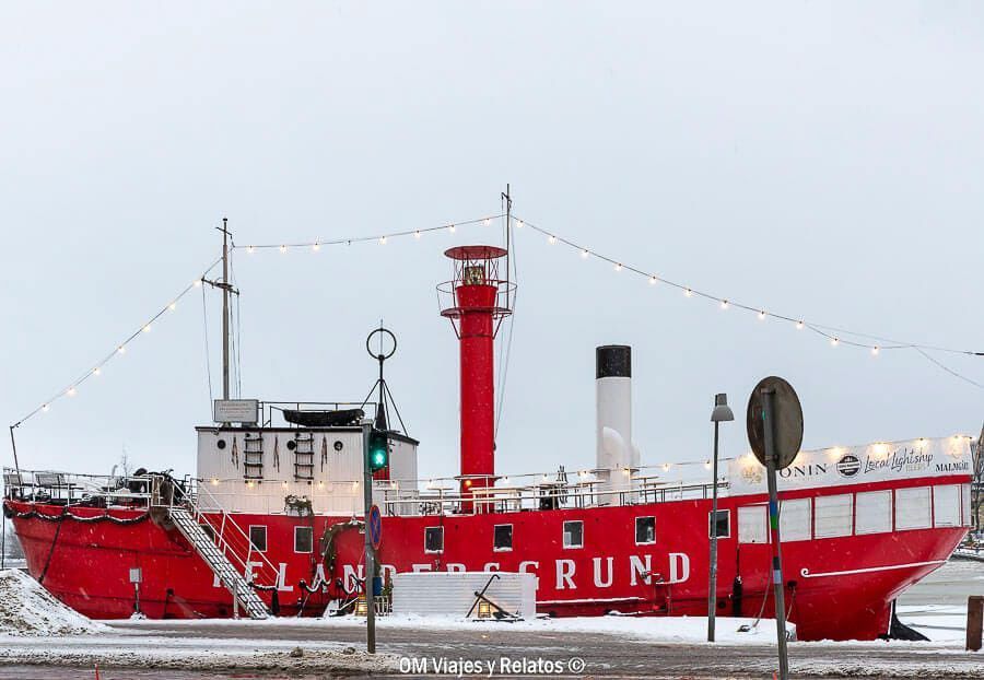 Relandersgrund, barco faro rojo entre la nieve del puerto, parada fotogénica que ver en Helsinki en un día