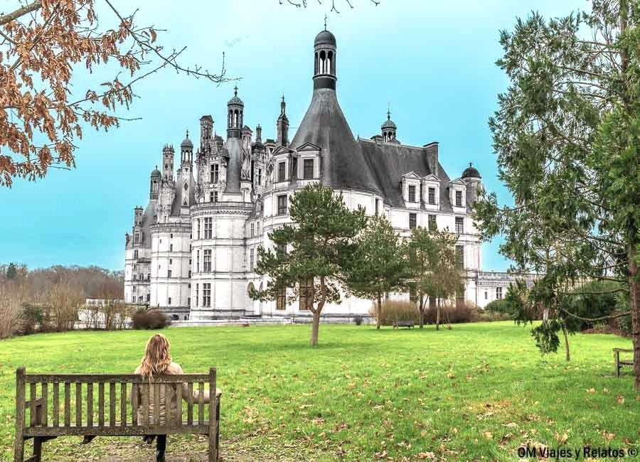Foto mía contemplando el majestuoso castillo de Chambord desde un banco en sus jardines, una de las estampas más icónicas de una ruta por los castillos del Loira en coche.