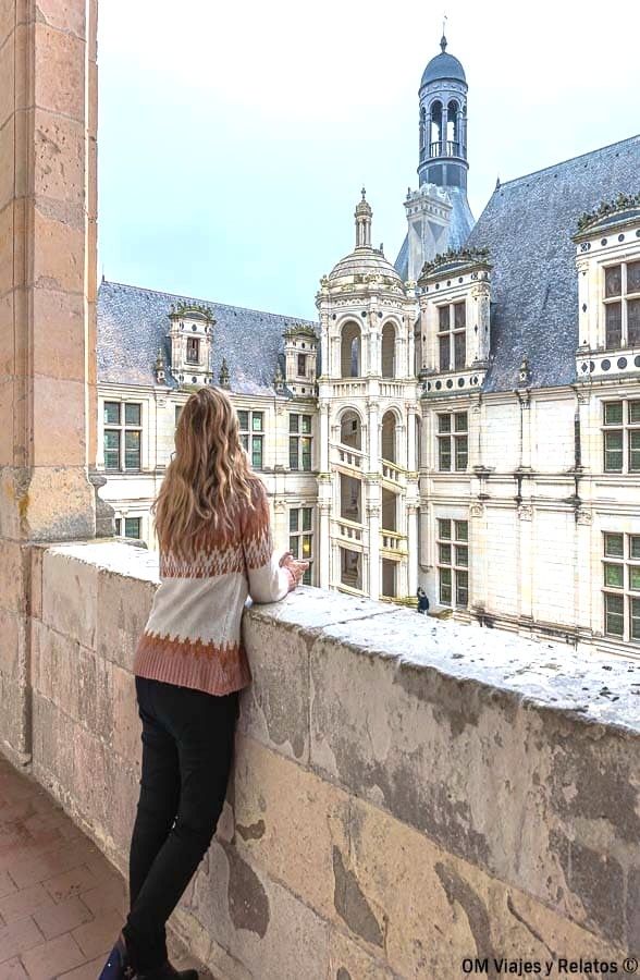 Foto mía admirando la famosa escalera de doble hélice del castillo de Chambord desde una de sus galerías interiores, una obra maestra del Renacimiento francés imprescindible en una ruta por los castillos del Loira en coche.