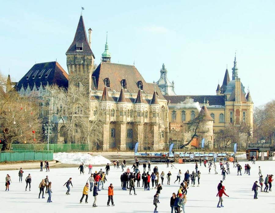 Personas patinando sobre hielo frente al Castillo Vajdahunyad en Budapest durante el invierno.