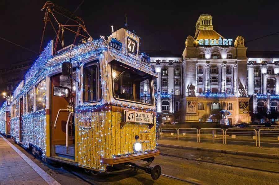 Tranvía navideño decorado con luces frente al Hotel Gellért en Budapest en Navidad