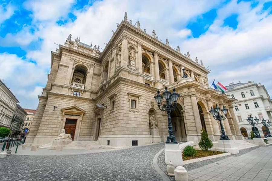 Fachada principal de la Ópera Estatal de Hungría en Budapest con cielo parcialmente nublado.