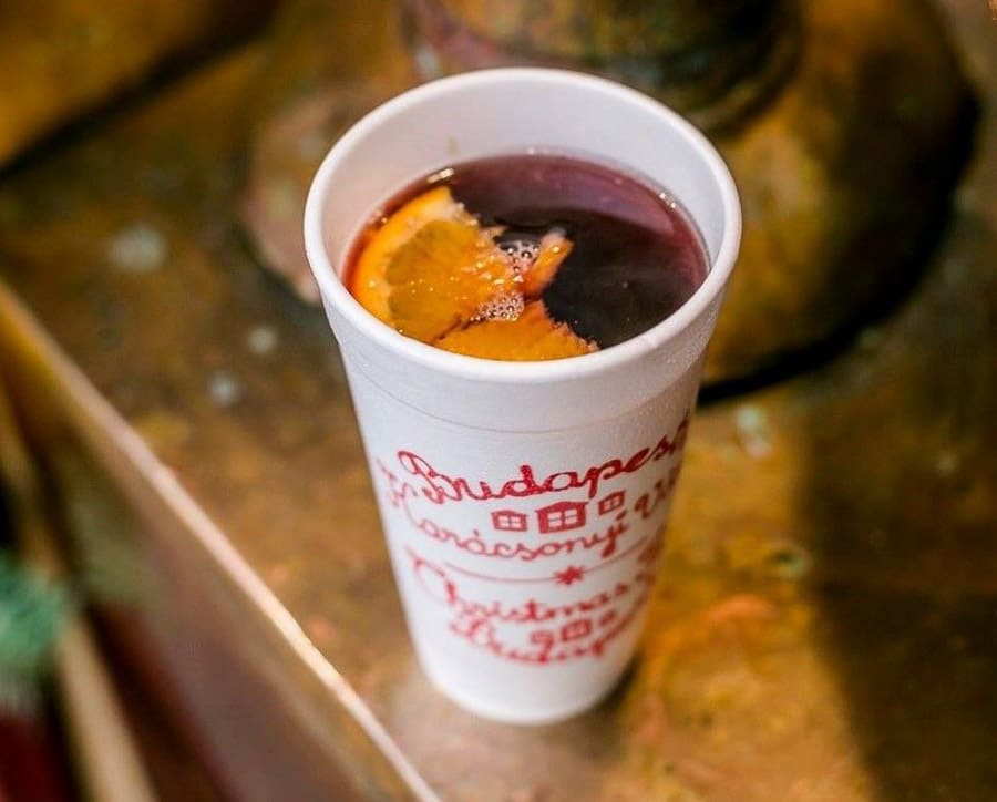 Vaso de vino caliente con especias y naranja en mercado navideño – Tradición de Budapest en Navidad