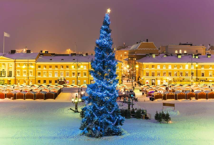 Vista nocturna de la Plaza del Senado nevada con árbol de Navidad y mercado navideño en Helsinki en Navidad