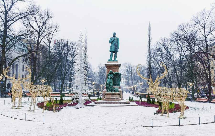 Parque nevado con estatua central y renos de luces navideñas en Helsinki en Navidad
