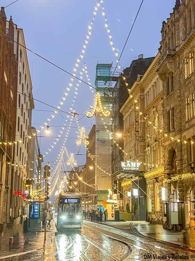 Tranvía circulando por calle mojada decorada con luces navideñas en Helsinki en Navidad
