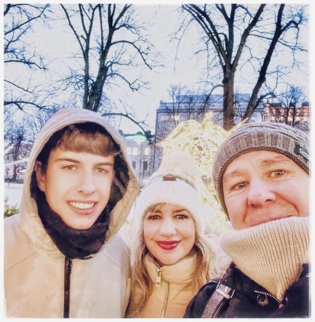 Selfie familiar de OMVIAJESYRELATOS abrigados entre luces navideñas en un parque de Helsinki en Navidad
