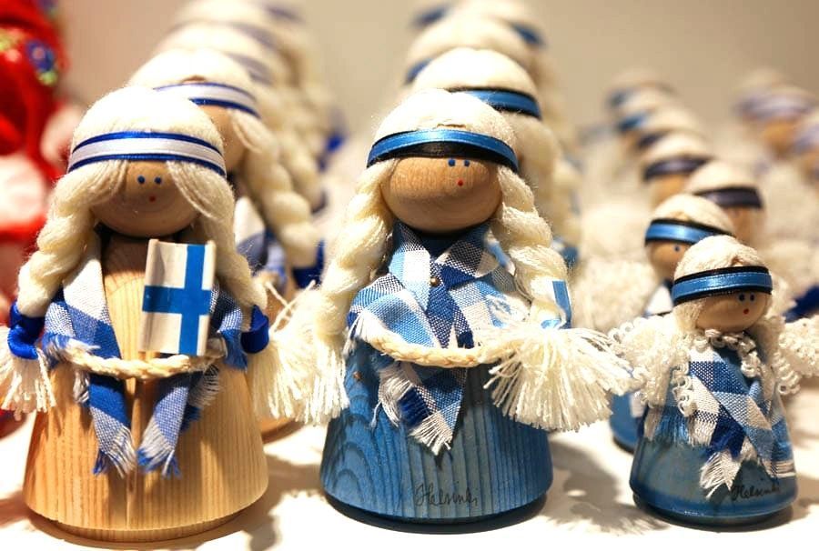 Muñecas de madera artesanales con los colores de la bandera de Finlandia en una tienda de recuerdos de Helsinki en Navidad