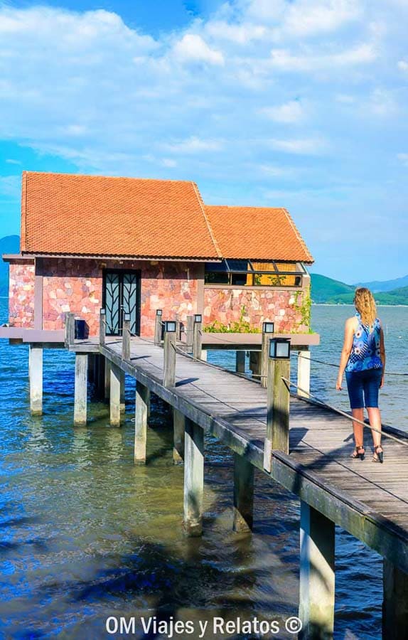 Una servidora caminando por un muelle frente a una casa sobre pilotes en Vietnam, experiencia tranquila dentro de los imprescindibles de Vietnam.