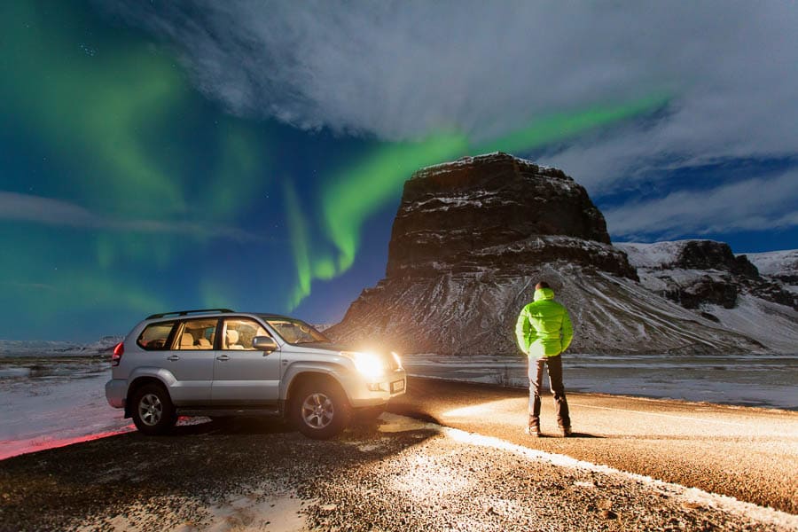 Islandia en febrero: auroras boreales sobre la carretera nevada y JC junto a su coche