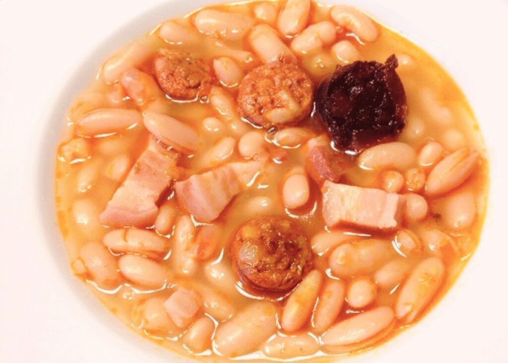Plato de alubias blancas con chorizo, morcilla y panceta, guiso tradicional para disfrutar en Chinchón que ver y donde comer