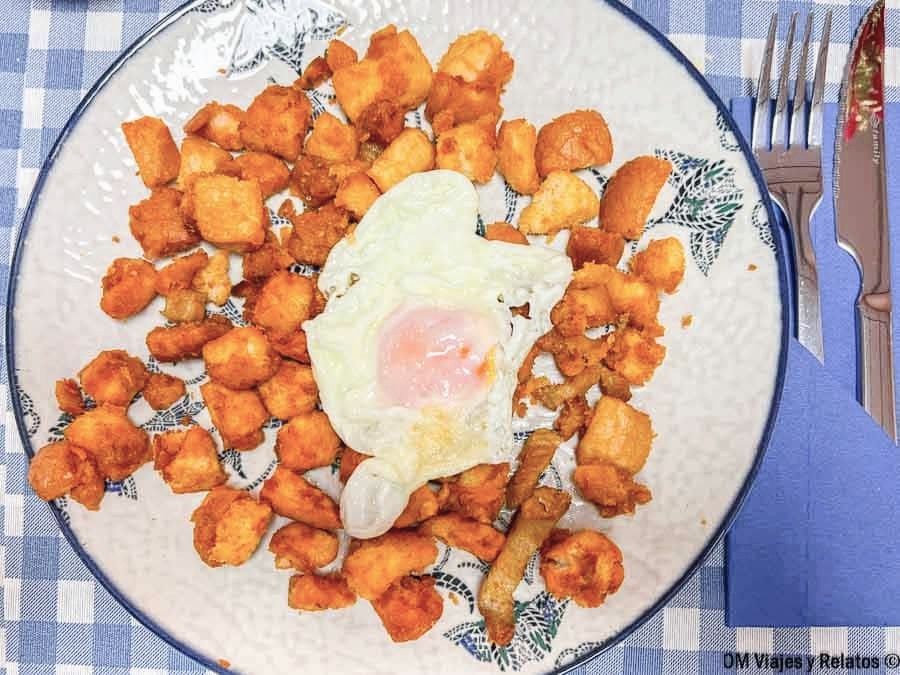 Ración de migas con huevo en plato de cerámica, comida popular para disfrutar en Chinchón que ver y donde comer