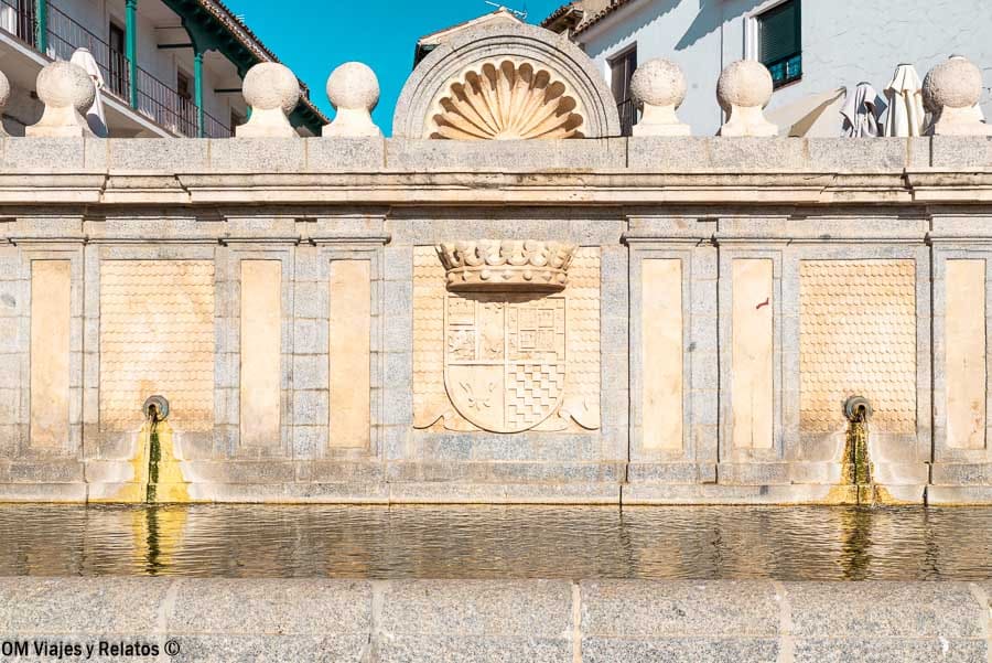 Fuente monumental con escudo heráldico en Chinchón reflejada en el agua Chinchón que ver y donde comer